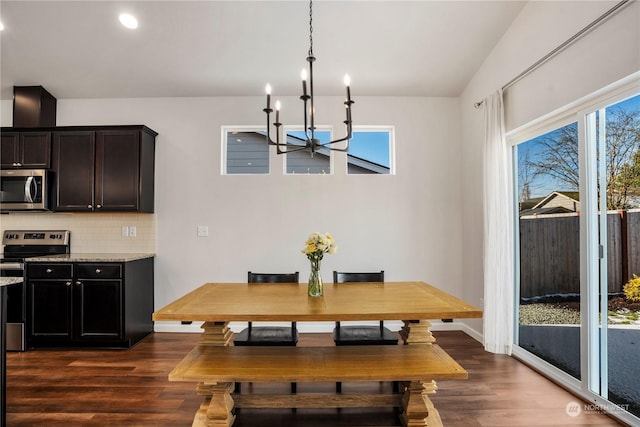 dining room with lofted ceiling, a notable chandelier, and dark wood-type flooring