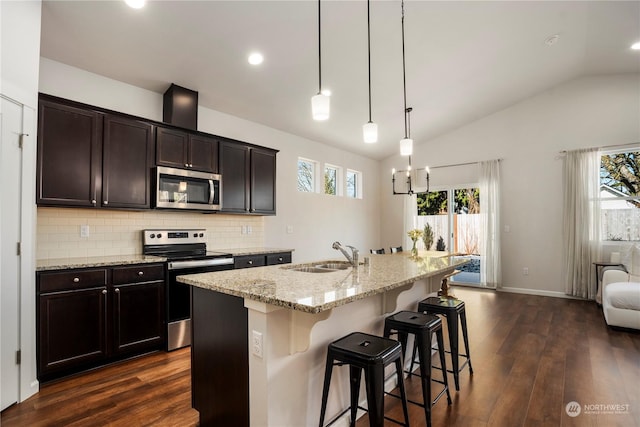 kitchen featuring sink, hanging light fixtures, a kitchen breakfast bar, stainless steel appliances, and a kitchen island with sink