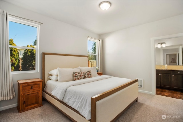 bedroom with ensuite bathroom and carpet