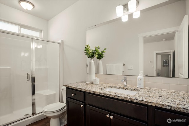 bathroom featuring vanity, toilet, an enclosed shower, and decorative backsplash