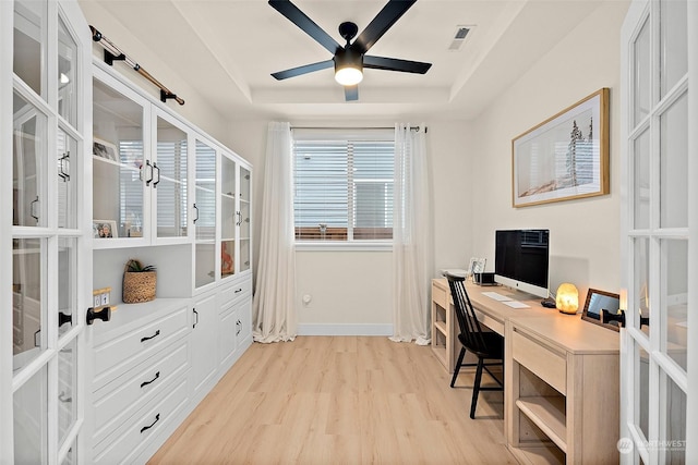 office space with a raised ceiling, ceiling fan, french doors, and light hardwood / wood-style flooring