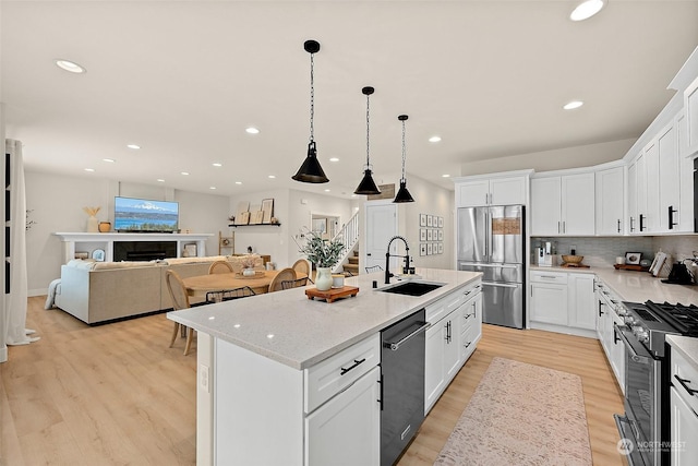 kitchen featuring a kitchen island with sink, sink, stainless steel appliances, and white cabinets