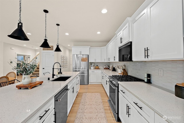 kitchen with white cabinetry, appliances with stainless steel finishes, sink, and light stone counters