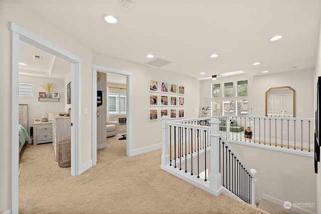 hallway featuring a healthy amount of sunlight and light colored carpet