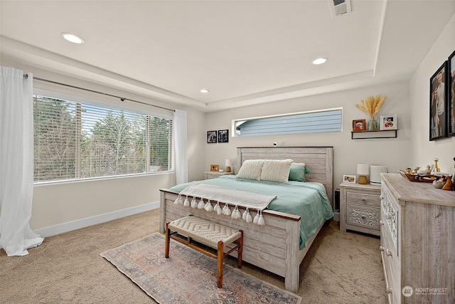 bedroom featuring a raised ceiling and light carpet