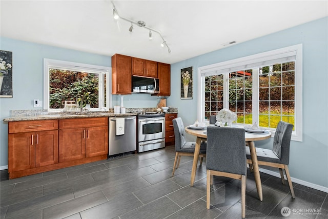 kitchen with light stone counters, visible vents, appliances with stainless steel finishes, a sink, and baseboards