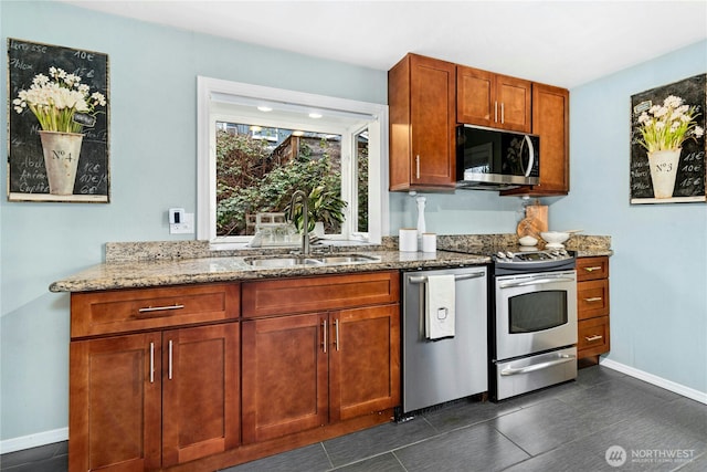 kitchen with baseboards, stainless steel appliances, a sink, and light stone countertops