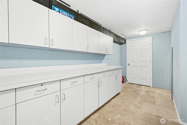 kitchen with light countertops, unfinished concrete flooring, and white cabinets