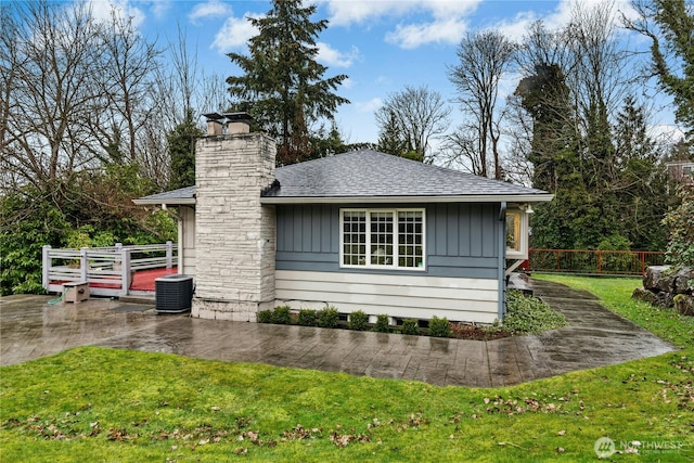 view of side of home featuring board and batten siding, a yard, a patio area, and fence