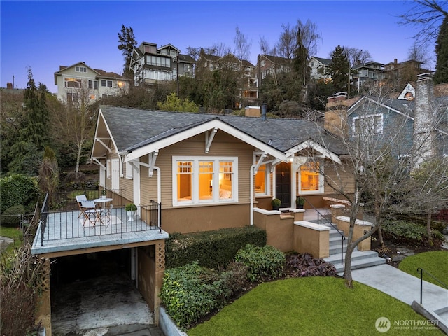 view of front of property with a deck, roof with shingles, a residential view, a chimney, and a front yard