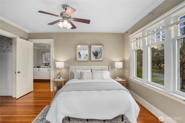 bedroom featuring ornamental molding, multiple windows, wood finished floors, and baseboards