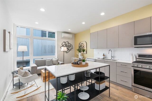 kitchen with a wall mounted air conditioner, sink, gray cabinetry, backsplash, and stainless steel appliances