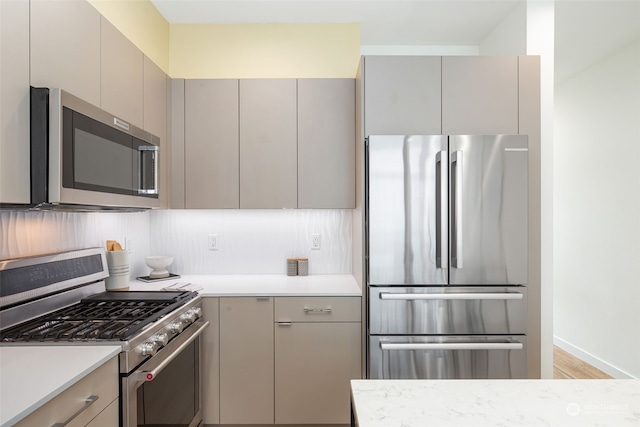 kitchen with backsplash, appliances with stainless steel finishes, light hardwood / wood-style floors, and gray cabinetry