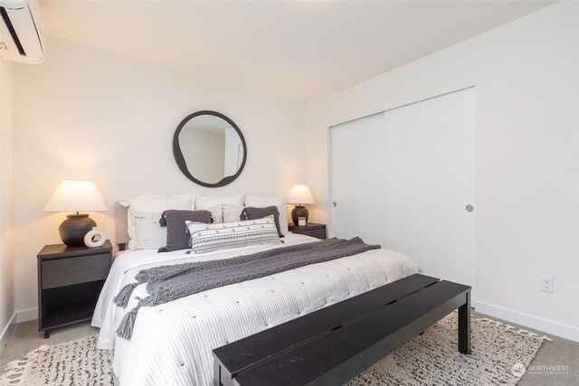 carpeted bedroom featuring a wall mounted air conditioner and a closet