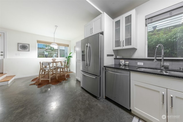 kitchen featuring appliances with stainless steel finishes, pendant lighting, white cabinetry, sink, and dark stone counters