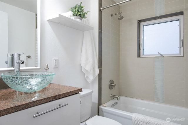 full bathroom with tiled shower / bath, vanity, and toilet