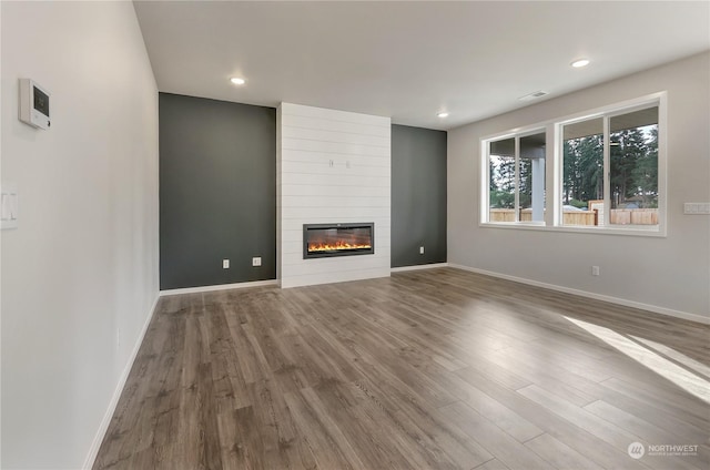 unfurnished living room with a large fireplace and hardwood / wood-style floors