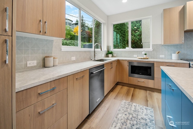 kitchen with stainless steel appliances, sink, backsplash, and light hardwood / wood-style flooring