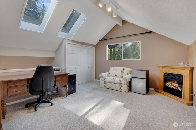 office area featuring track lighting, vaulted ceiling with skylight, light carpet, and a textured ceiling