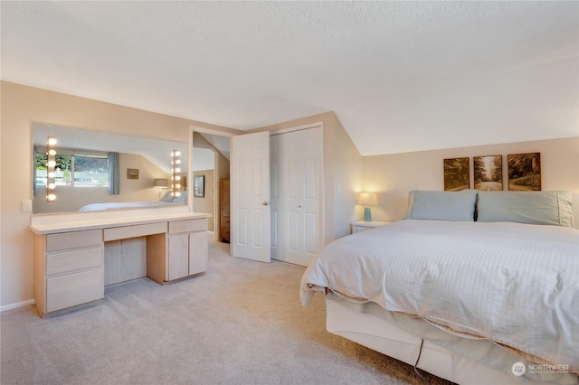 bedroom featuring vaulted ceiling, light colored carpet, a textured ceiling, and a closet