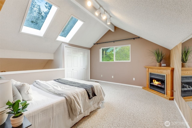 9230 119th St E, Puyallup, WA 98373 - bedroom featuring a warm lit fireplace, light colored carpet, a textured ceiling, baseboards, and vaulted ceiling with skylight