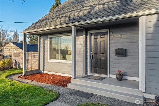 doorway to property featuring a shingled roof and fence