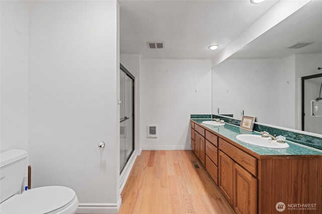 bathroom featuring vanity, heating unit, wood-type flooring, toilet, and walk in shower