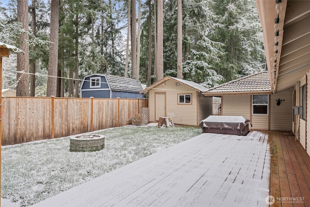 exterior space with an outdoor fire pit, a hot tub, a deck, and a shed