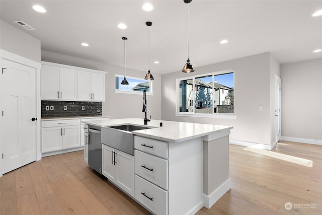 kitchen with decorative light fixtures, an island with sink, sink, white cabinets, and stainless steel dishwasher