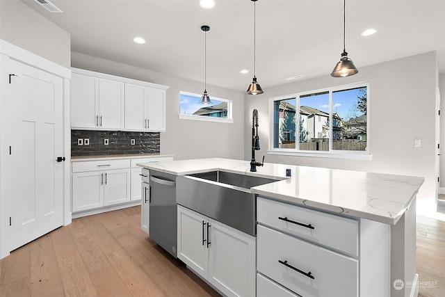 kitchen featuring hanging light fixtures, white cabinetry, a kitchen island with sink, and stainless steel dishwasher