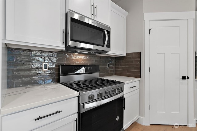 kitchen with white cabinetry, light stone countertops, decorative backsplash, and stainless steel appliances