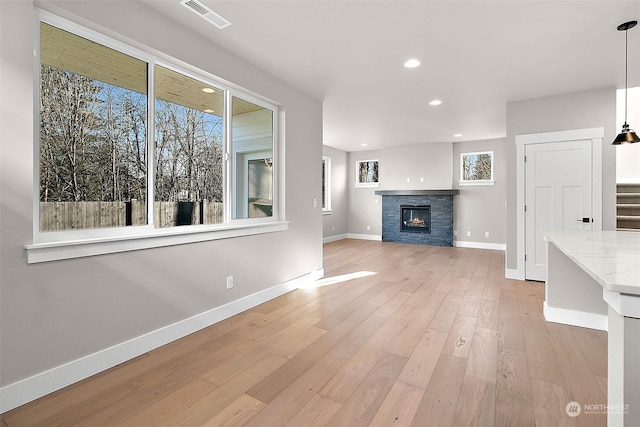 unfurnished living room featuring a stone fireplace and light hardwood / wood-style floors