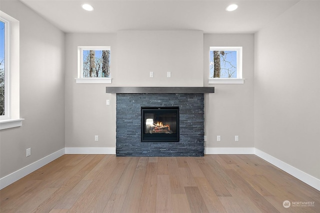 unfurnished living room with plenty of natural light, a fireplace, and light hardwood / wood-style flooring