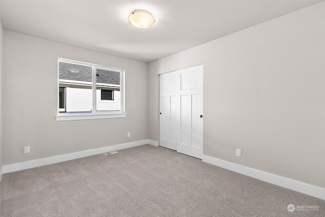 unfurnished bedroom with a closet and light carpet