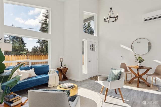 living room featuring hardwood / wood-style flooring, a towering ceiling, an inviting chandelier, and a wall unit AC