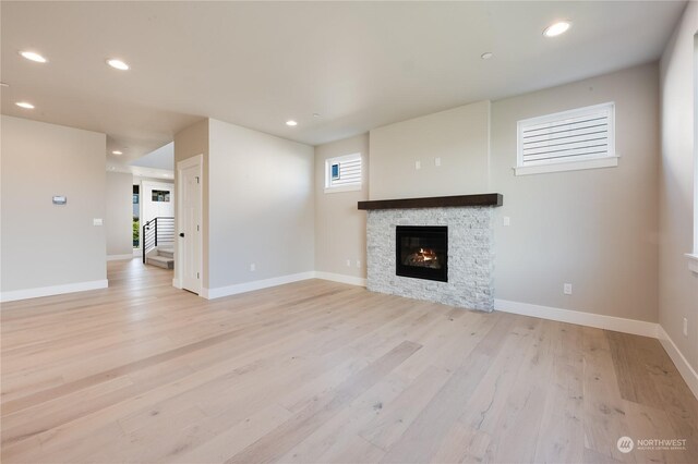 unfurnished living room with a stone fireplace and light hardwood / wood-style floors