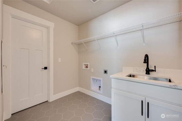 laundry room featuring sink, hookup for a washing machine, cabinets, dark tile patterned flooring, and hookup for an electric dryer