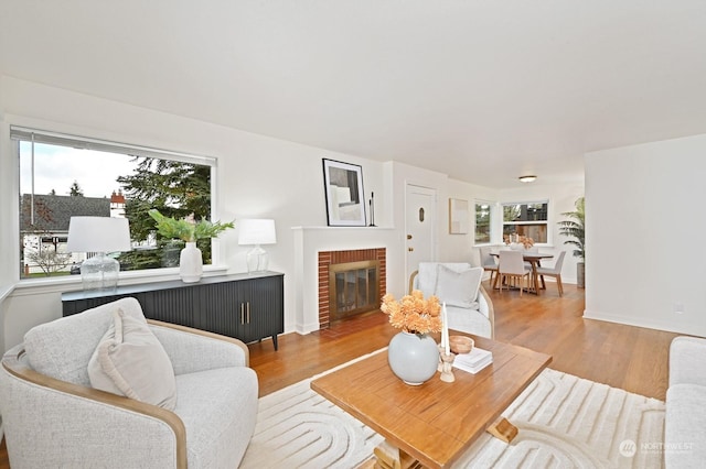 living room featuring a brick fireplace, plenty of natural light, and light hardwood / wood-style floors