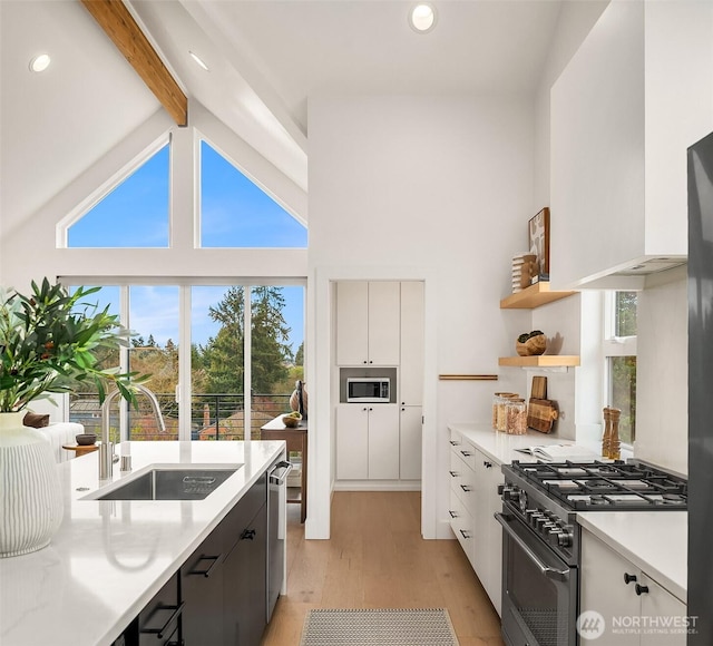 kitchen with beamed ceiling, sink, stainless steel appliances, and white cabinetry