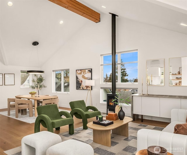 living room with beamed ceiling, light wood-type flooring, high vaulted ceiling, and a wood stove