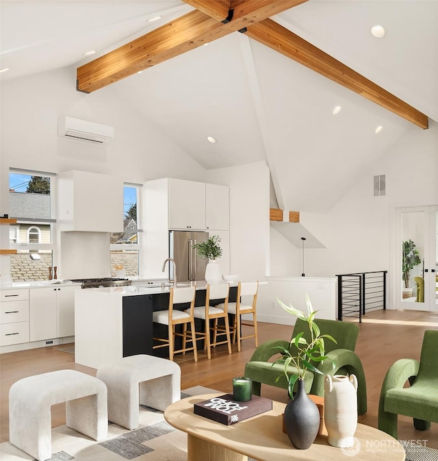 living room featuring a wall unit AC, high vaulted ceiling, light wood-type flooring, and beam ceiling