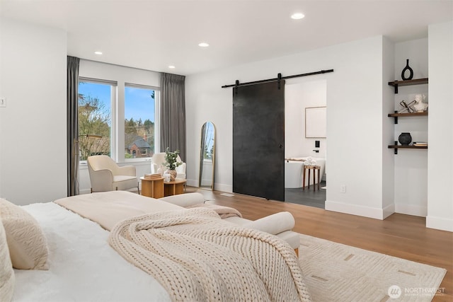 bedroom with hardwood / wood-style flooring and a barn door