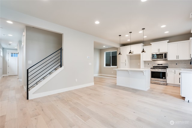 kitchen featuring pendant lighting, stainless steel appliances, a center island, and white cabinets