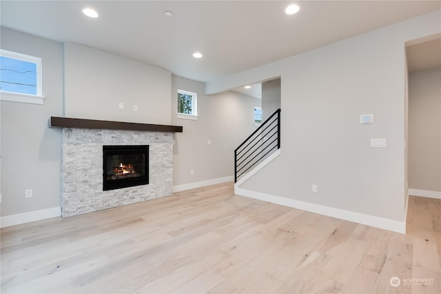 unfurnished living room with a stone fireplace, a healthy amount of sunlight, and light hardwood / wood-style flooring