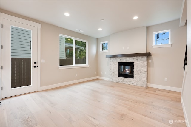 unfurnished living room with a stone fireplace and light hardwood / wood-style flooring