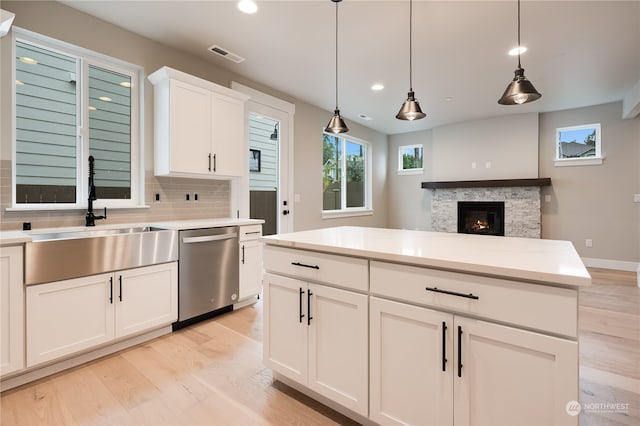 kitchen with sink, white cabinetry, tasteful backsplash, stainless steel dishwasher, and pendant lighting