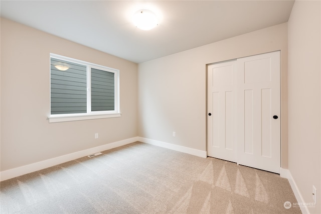 unfurnished bedroom with a closet and light carpet