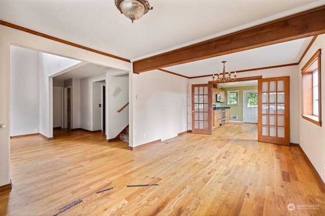 spare room featuring beam ceiling, ornamental molding, french doors, and light wood-type flooring