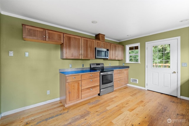 kitchen featuring ornamental molding, appliances with stainless steel finishes, and light hardwood / wood-style floors