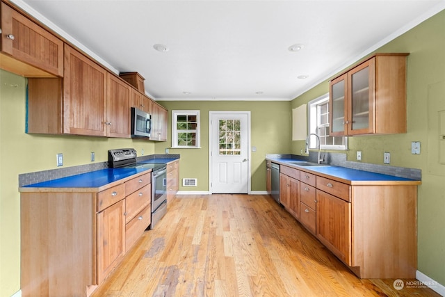 kitchen with stainless steel appliances, crown molding, sink, and light hardwood / wood-style flooring